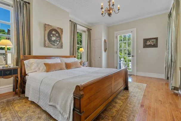 Representative hotel space: A bedroom with a wooden bed, pale bedding, and windows.