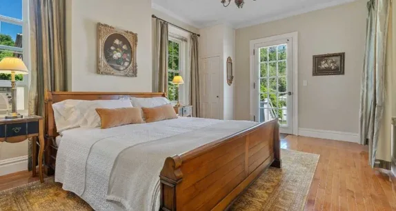Representative hotel space: A bedroom with a wooden bed, pale bedding, and a glass-paned door.