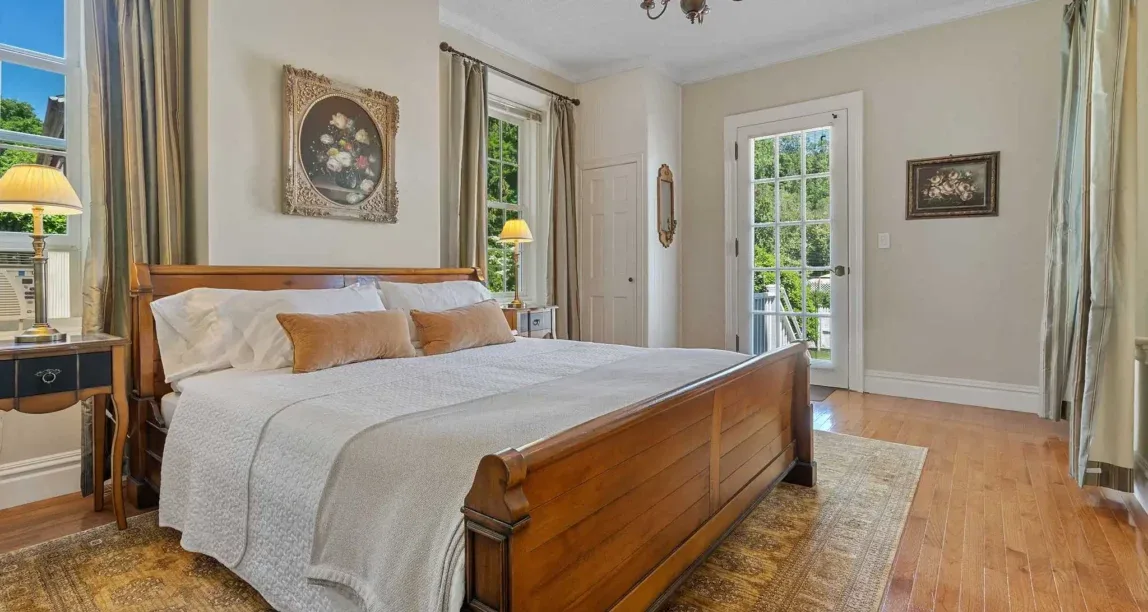 Representative hotel space: A bedroom with a large bed, wood furnishings, and windows opening onto a balcony.