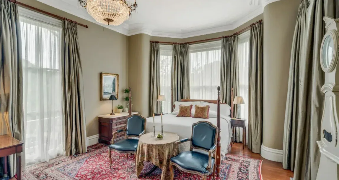 Representative hotel space: A bedroom with a bed, seating, and tall curtained windows.