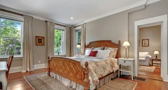 Representative hotel space: A bedroom with a wooden bed, bedside tables, and tall windows.