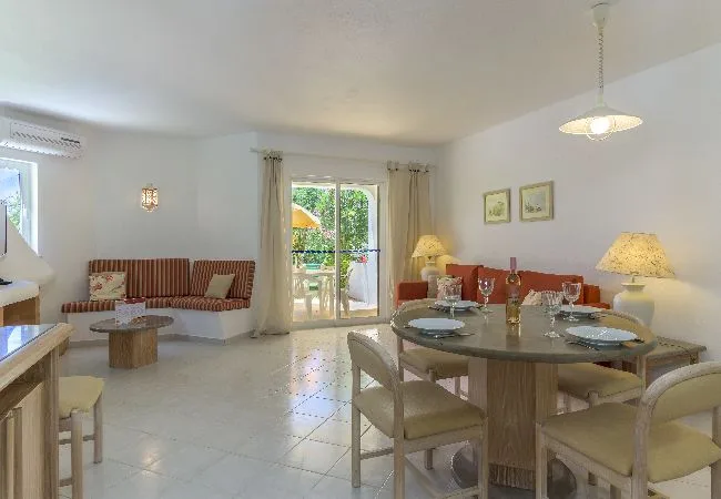 A bright dining area with a table and chairs beside a sitting area.