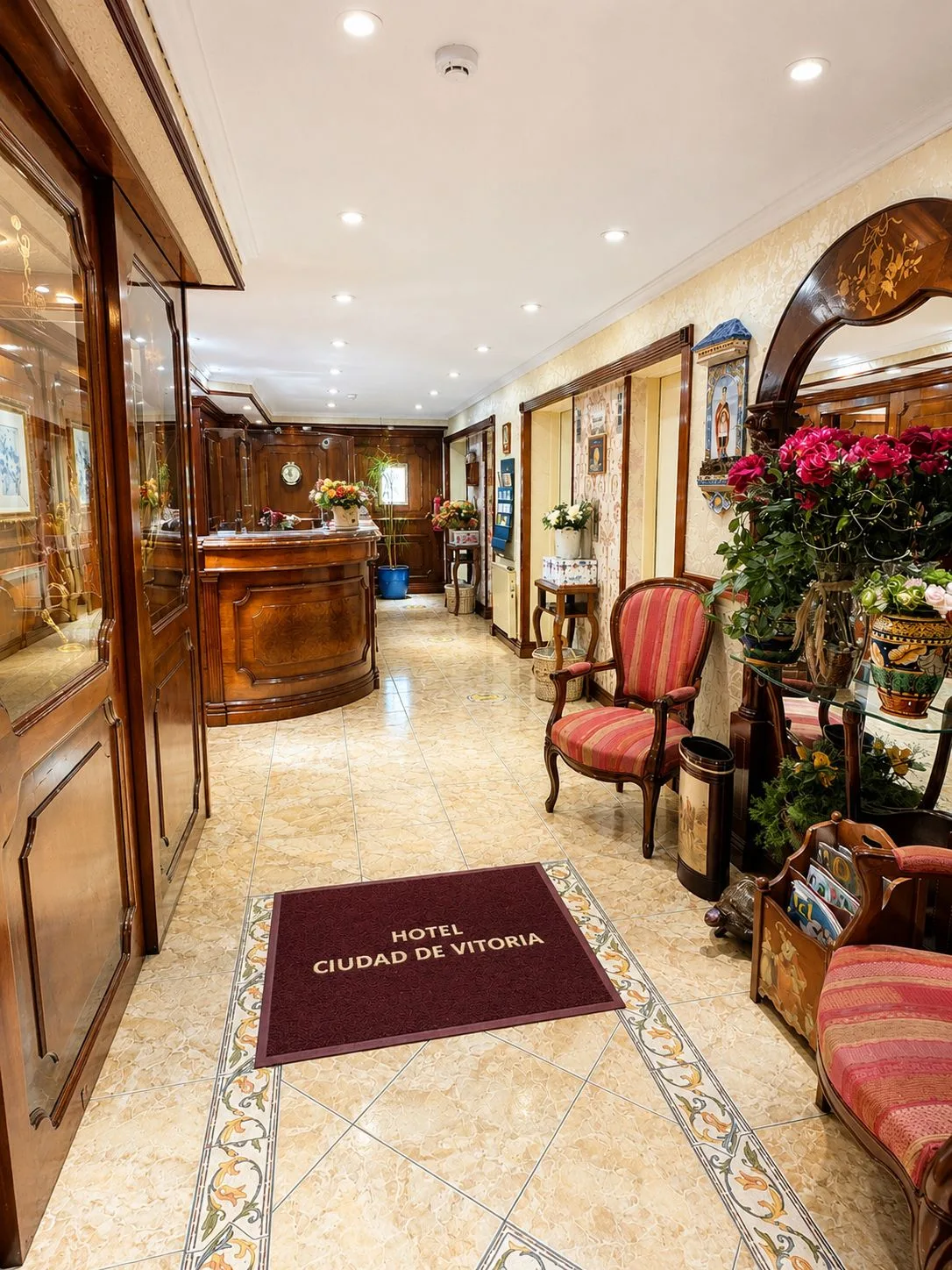 Espacio representativo del hotel: Vestíbulo de hotel con mostrador de recepción y asientos junto al suelo de baldosas.