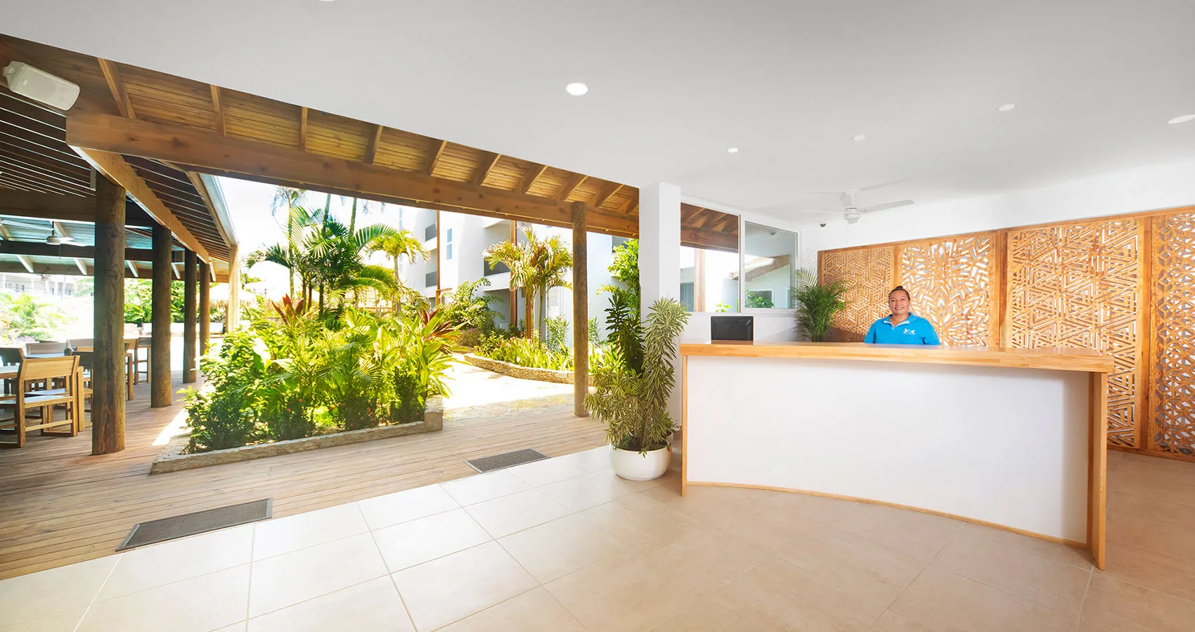 Espacio representativo del hotel: Área de recepción del hotel con un mostrador y un patio con plantas.