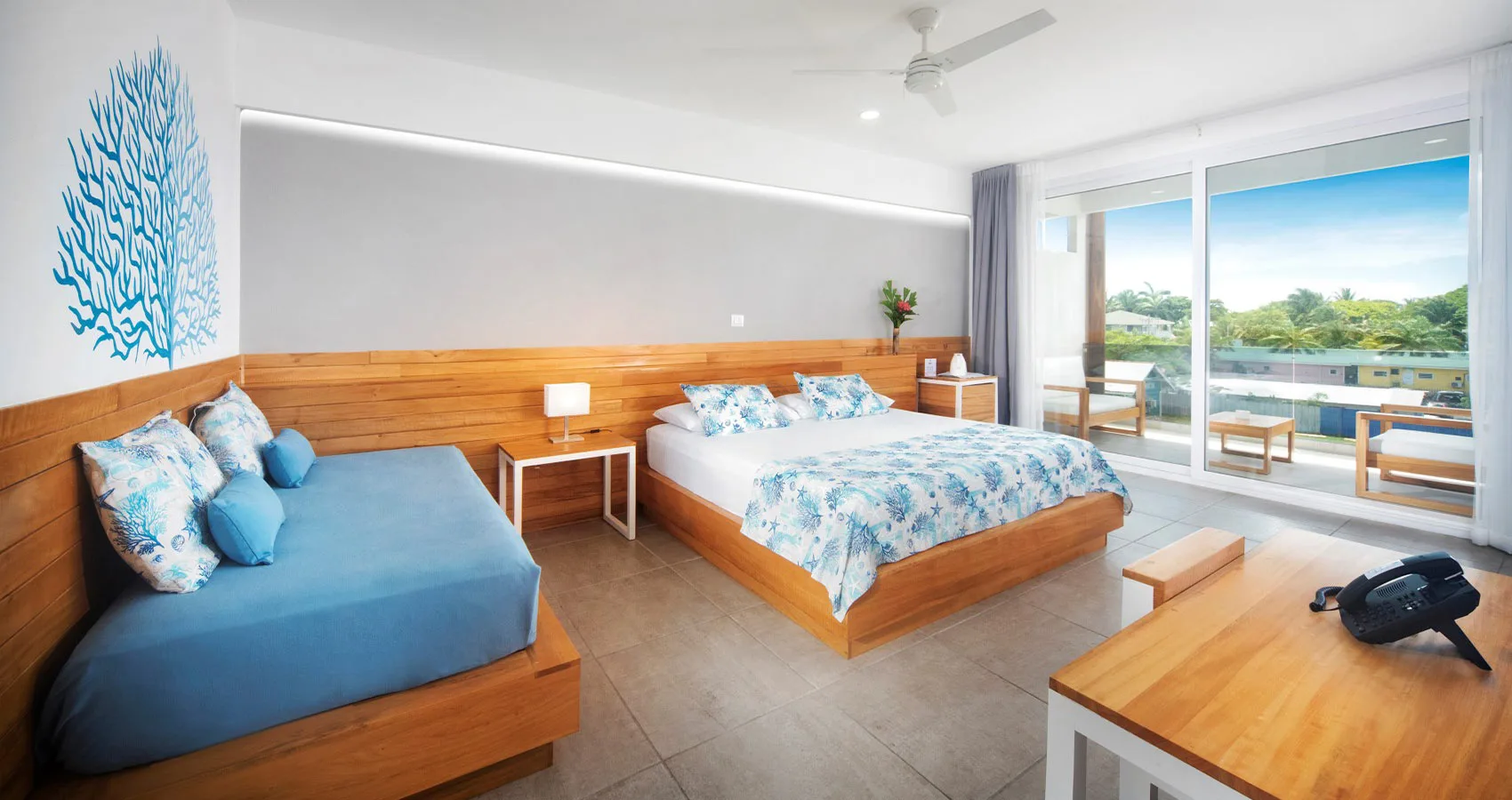 Espacio representativo del hotel: Un dormitorio con camas, muebles de madera y puertas corredizas de vidrio hacia un balcón.