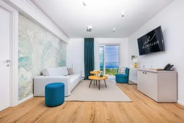 Representative hotel space: A bright hotel room with seating, a rug, and a window overlooking the water.