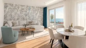 Representative hotel space: A bright living and dining area with seating beside large windows.
