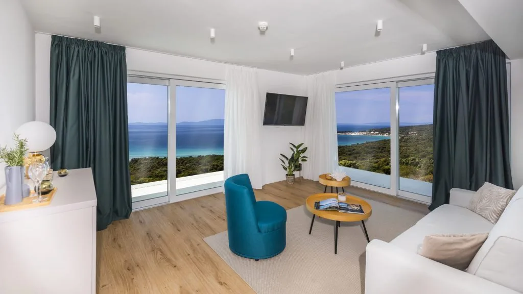 Representative hotel space: A bright living room has large windows overlooking the sea.