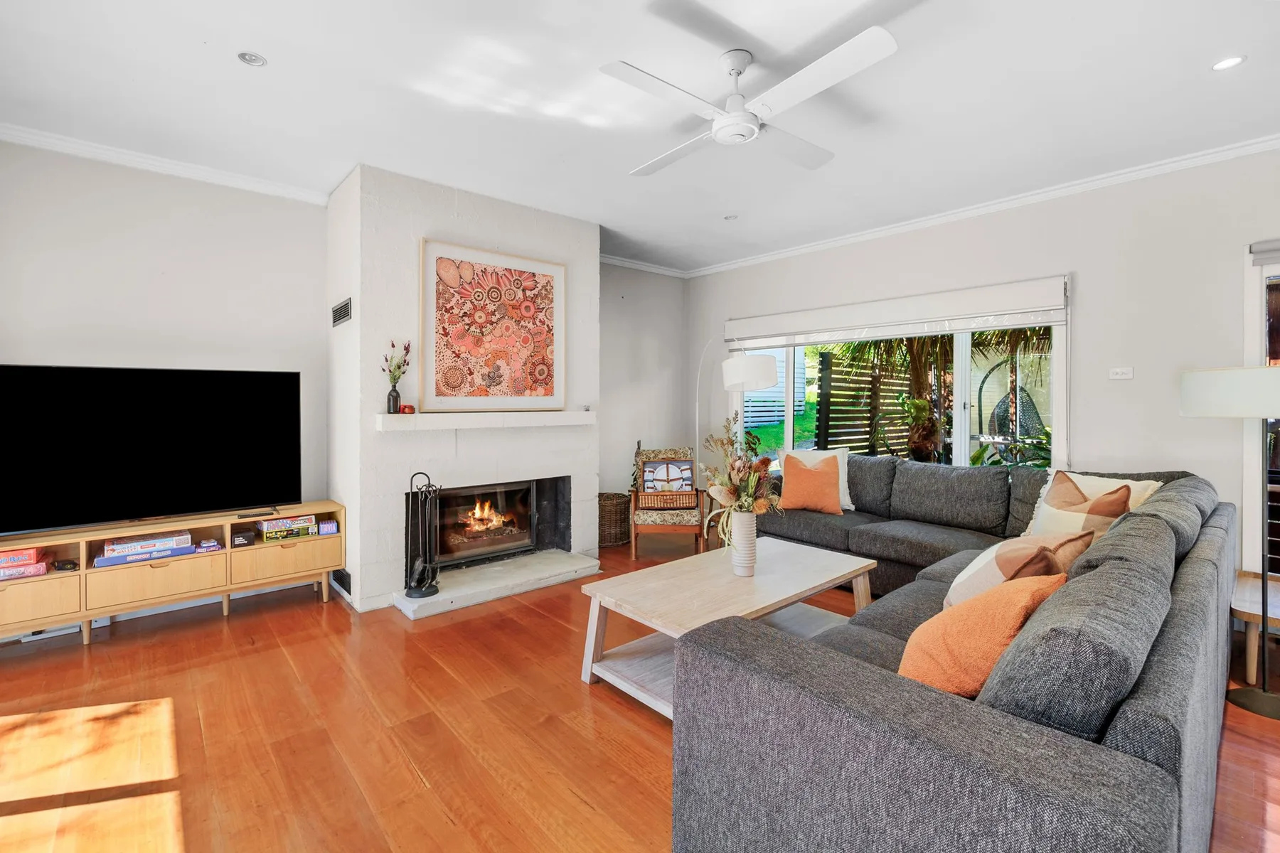 A living room with gray seating, a fireplace, and a television.