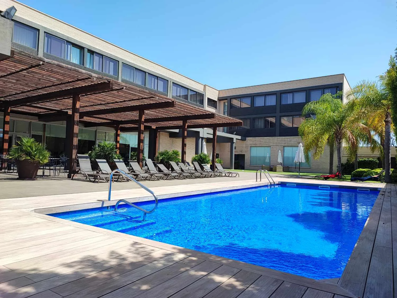 Representative hotel space: An outdoor swimming pool beside a modern hotel building and patio seating.