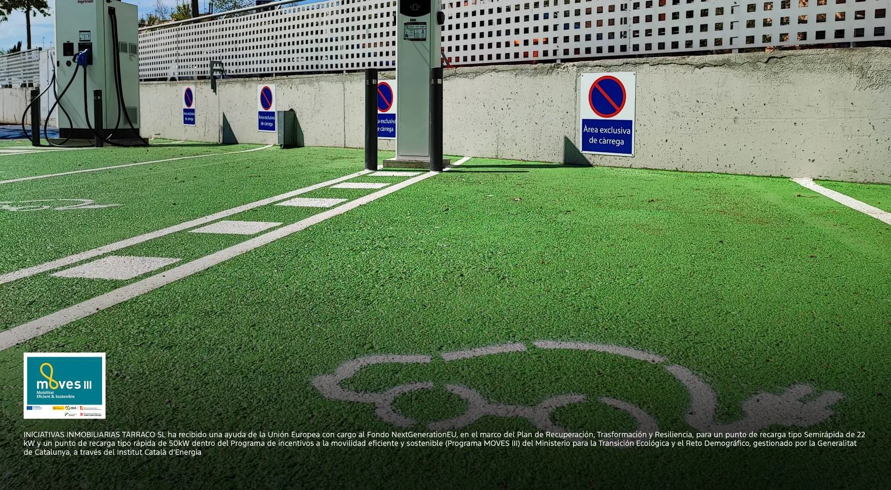 Representative hotel space: A marked parking area with green pavement and charging stations beside a wall.