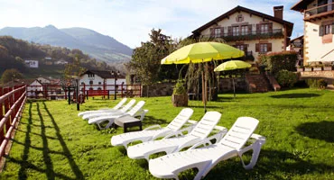 Representative hotel space: A sunny garden lounge with white reclining seats and green umbrellas.