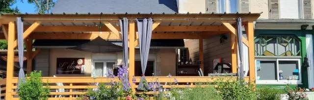 Representative hotel space: An outdoor dining area sits under a wooden pergola beside the building.
