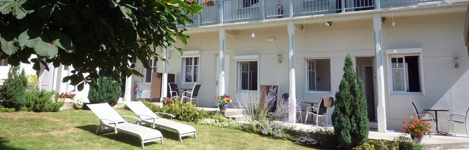 Representative hotel space: A garden patio with lawn seating and flowering plants beside a building.