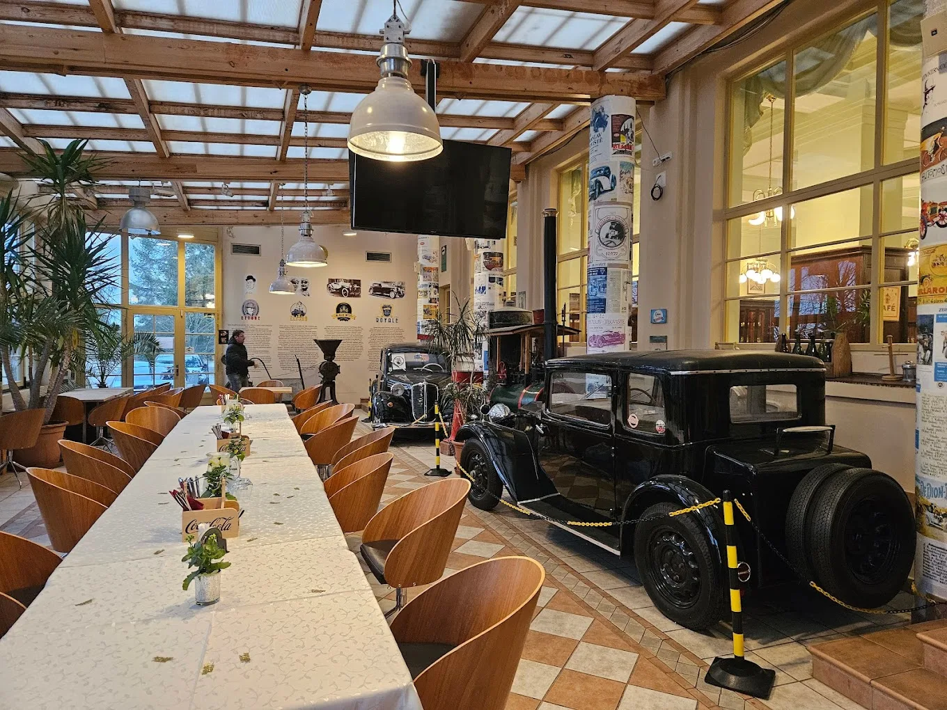 Espacio representativo del hotel: Un comedor con una mesa larga junto a una exhibición de autos antiguos.