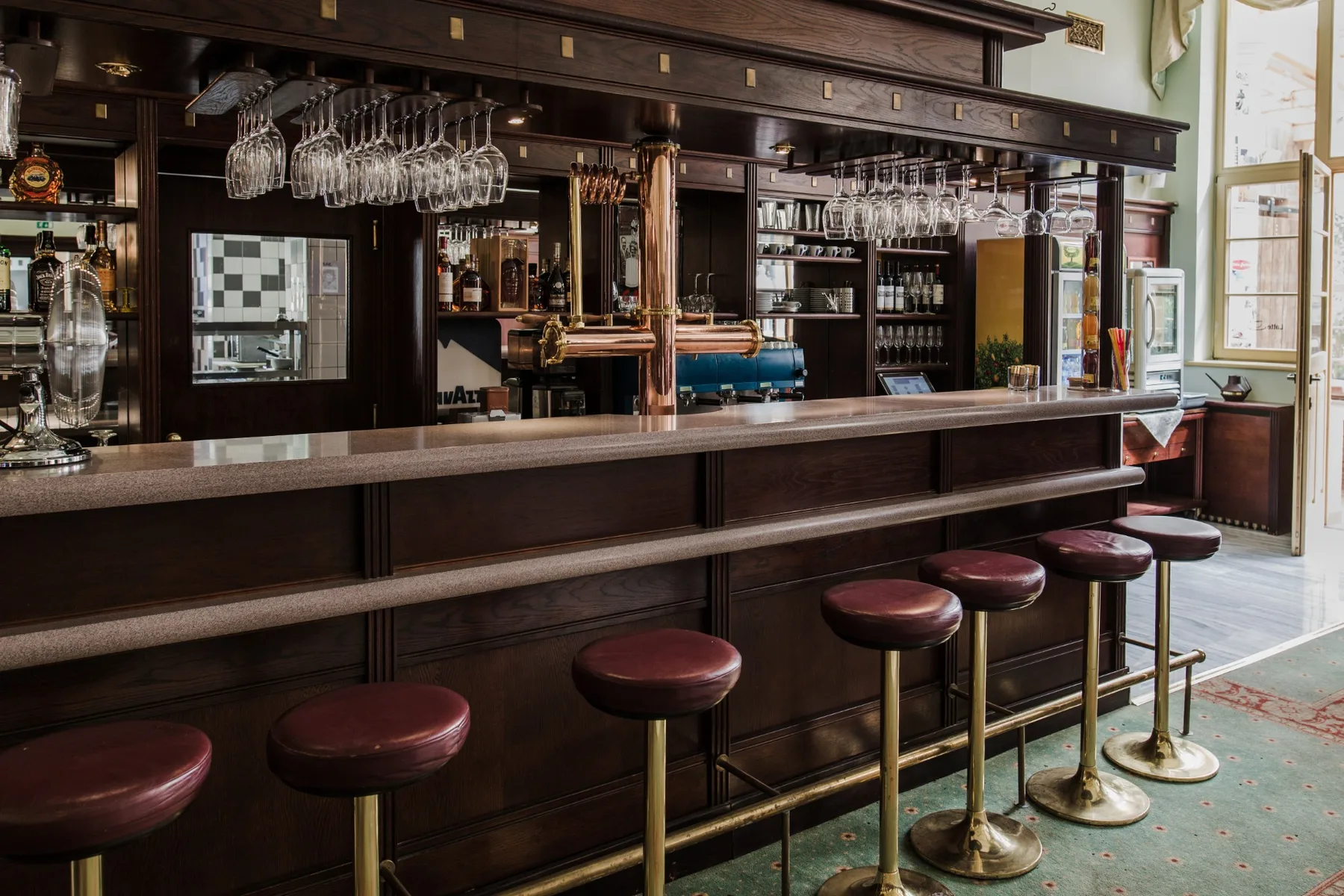 Espacio representativo del hotel: Una barra con taburetes y copas colgadas sobre ella.