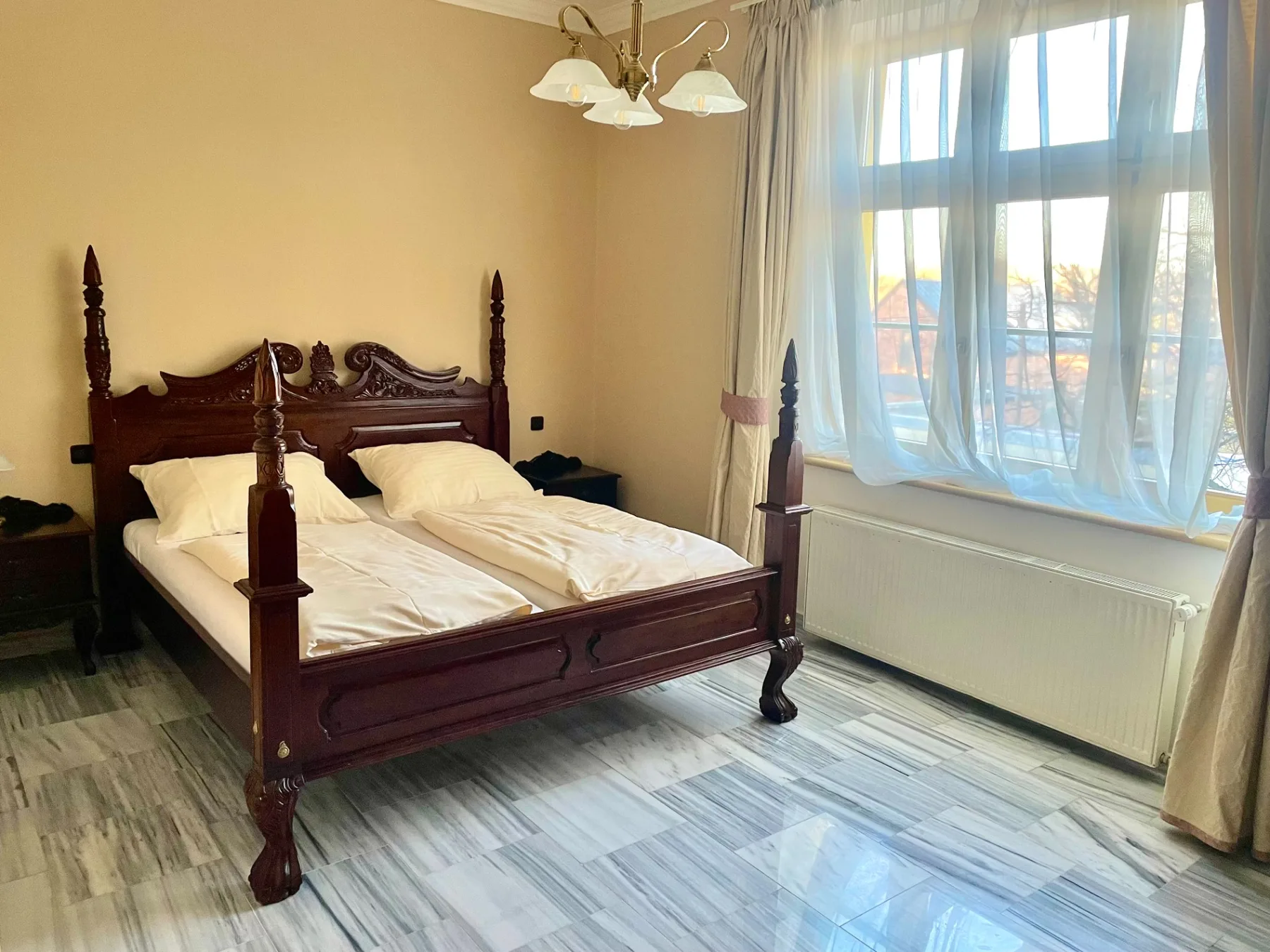Espacio representativo del hotel: Un dormitorio con una cama grande junto a una ventana luminosa.