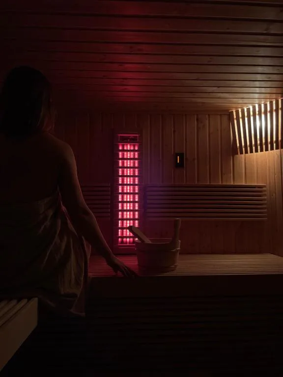 Espacio representativo del hotel: Una sauna tenue se ilumina con luz roja junto a bancos de madera.