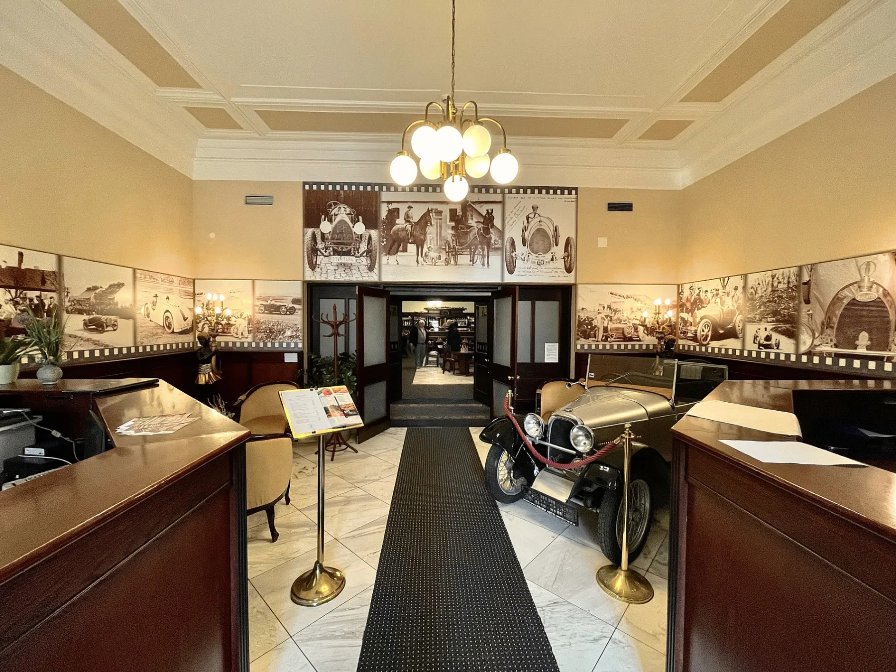 Espacio representativo del hotel: Un vestíbulo de hotel exhibe vehículos antiguos y arte histórico en las paredes.
