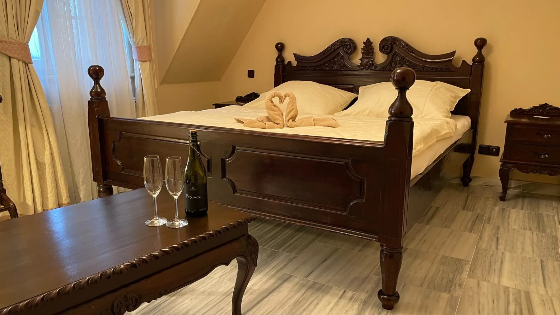 Espacio representativo del hotel: Dormitorio con una cama de madera oscura y una ventana con cortinas.