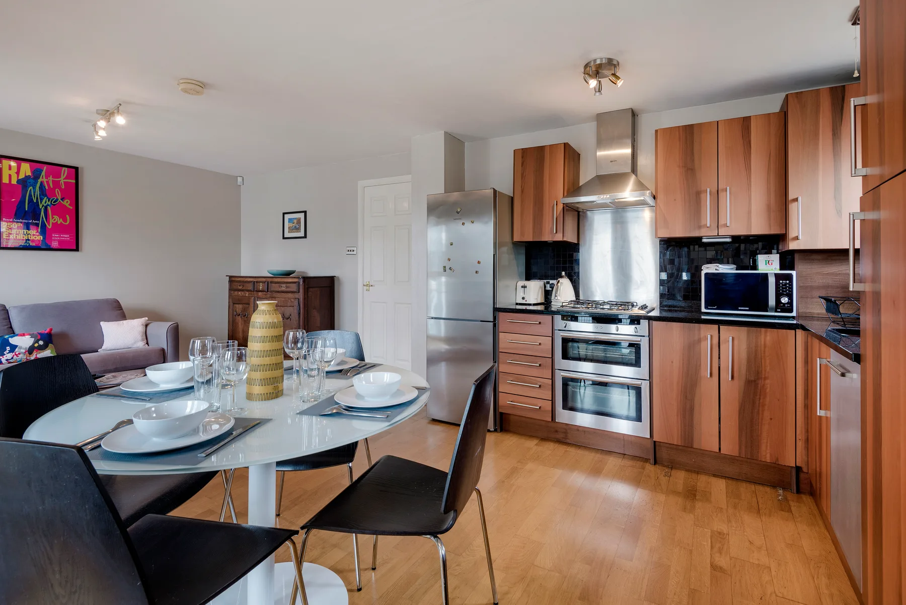 A dining area and kitchen with a set table and wooden cabinets.