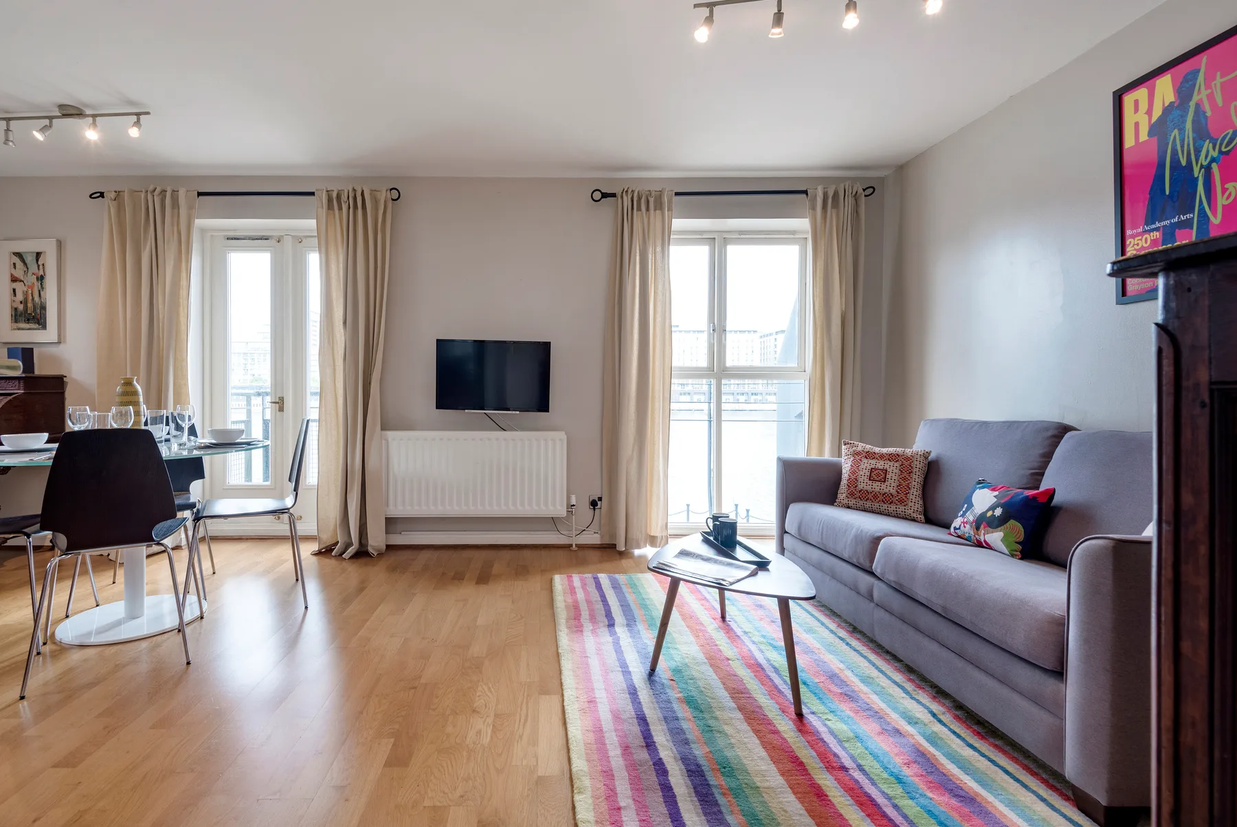A bright living room with a gray sofa, television, and colorful rug.