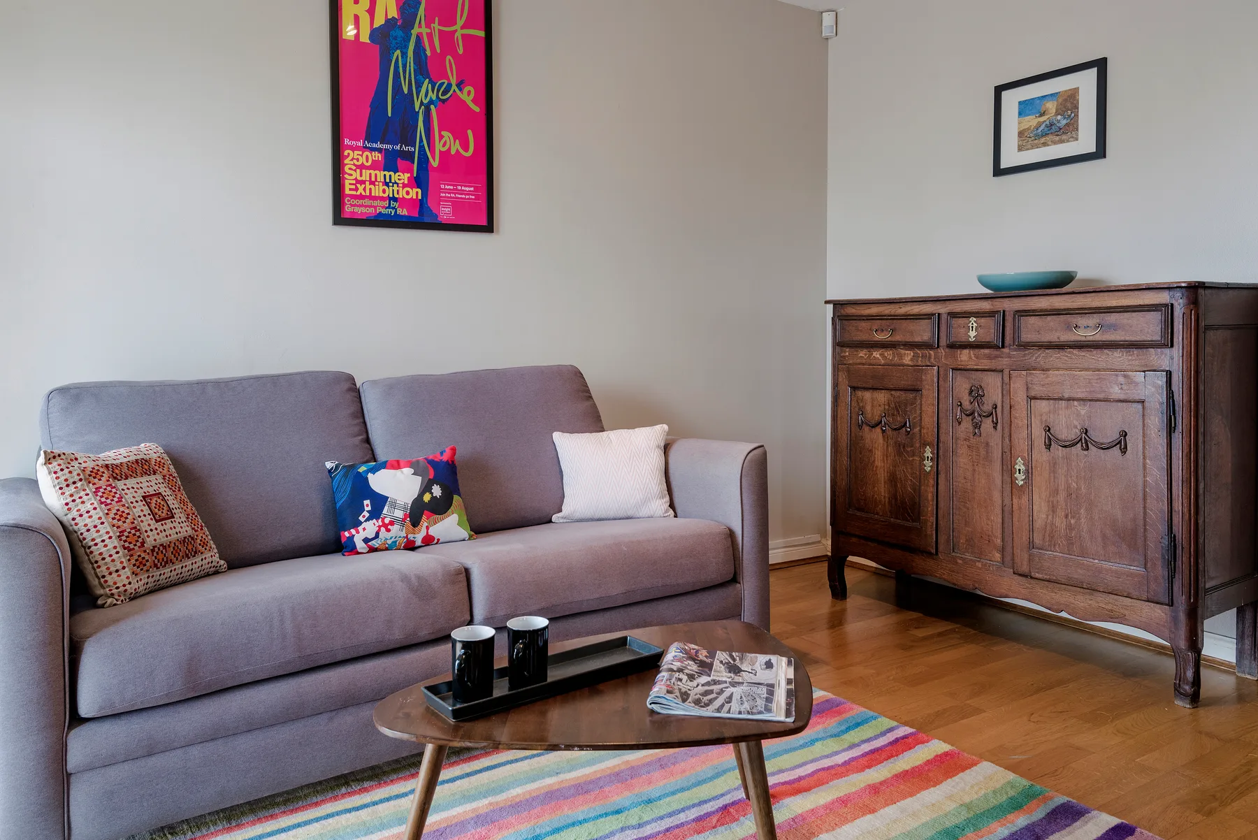 A living room with a sofa, wooden cabinet, and colorful rug.