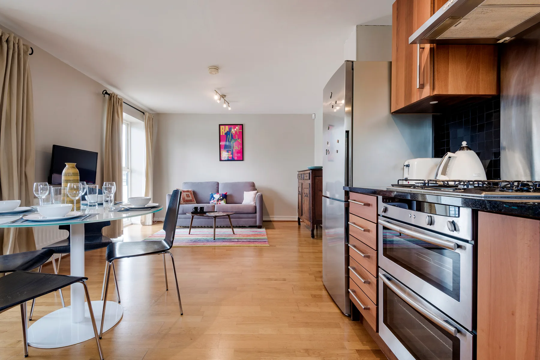 An open-plan living room and kitchen with a dining table and sofa.