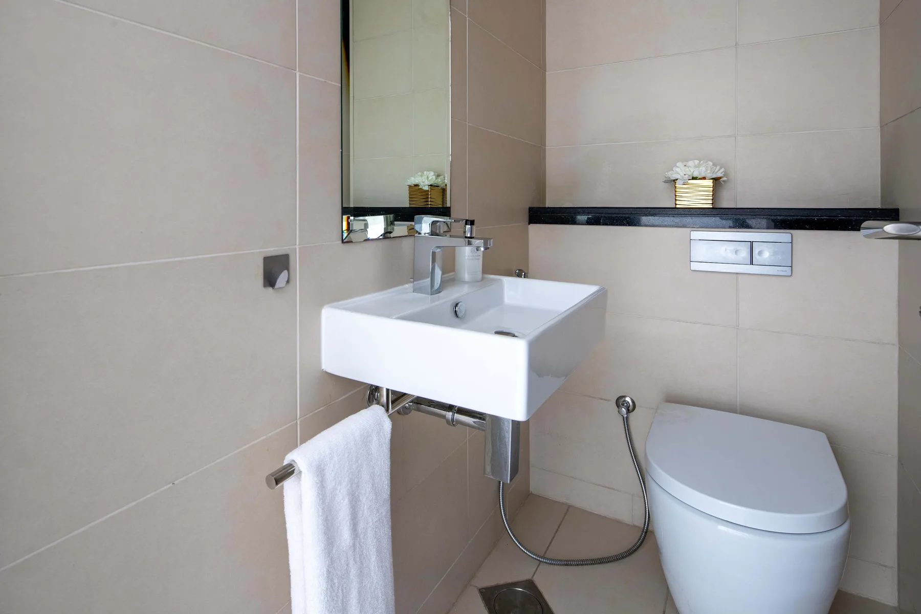 A tiled bathroom with a wall-mounted sink and toilet.