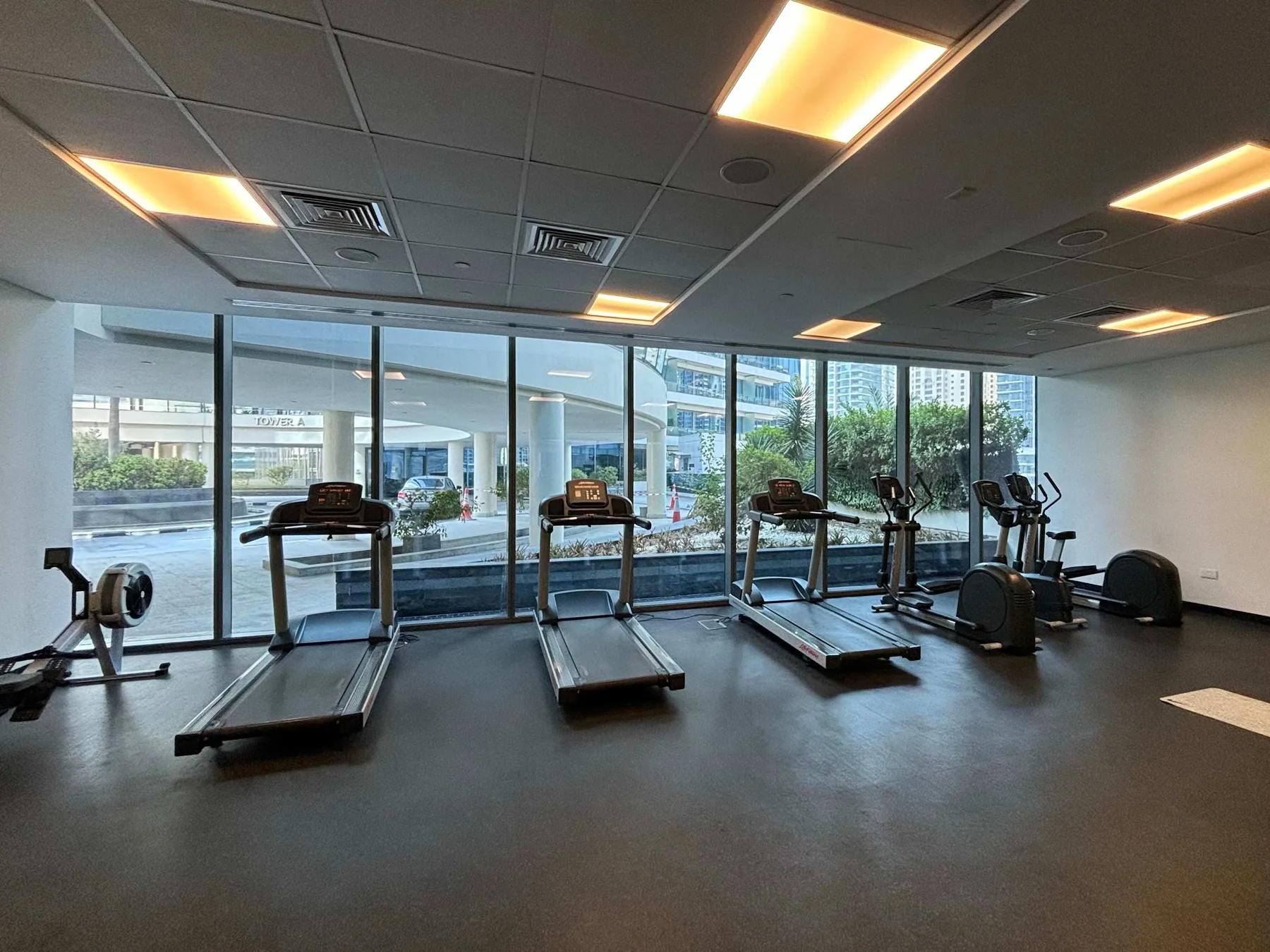 Shared amenity: A gym with treadmills and exercise bikes beside large windows.