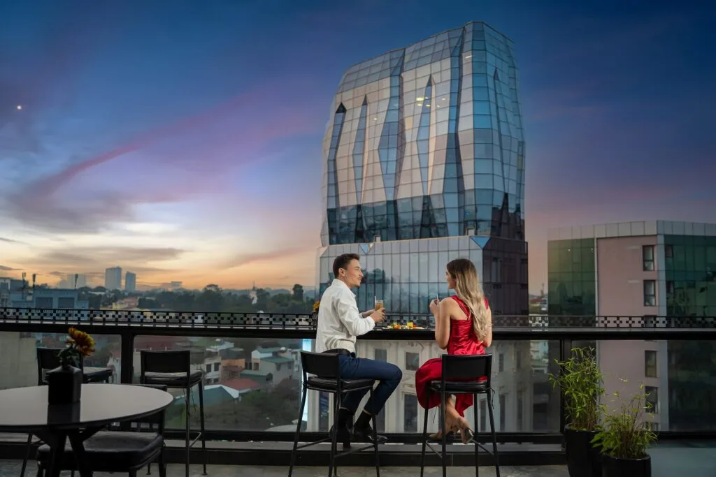 Espacio representativo del hotel: La zona de estar de una terraza en la azotea da a un horizonte urbano al atardecer.