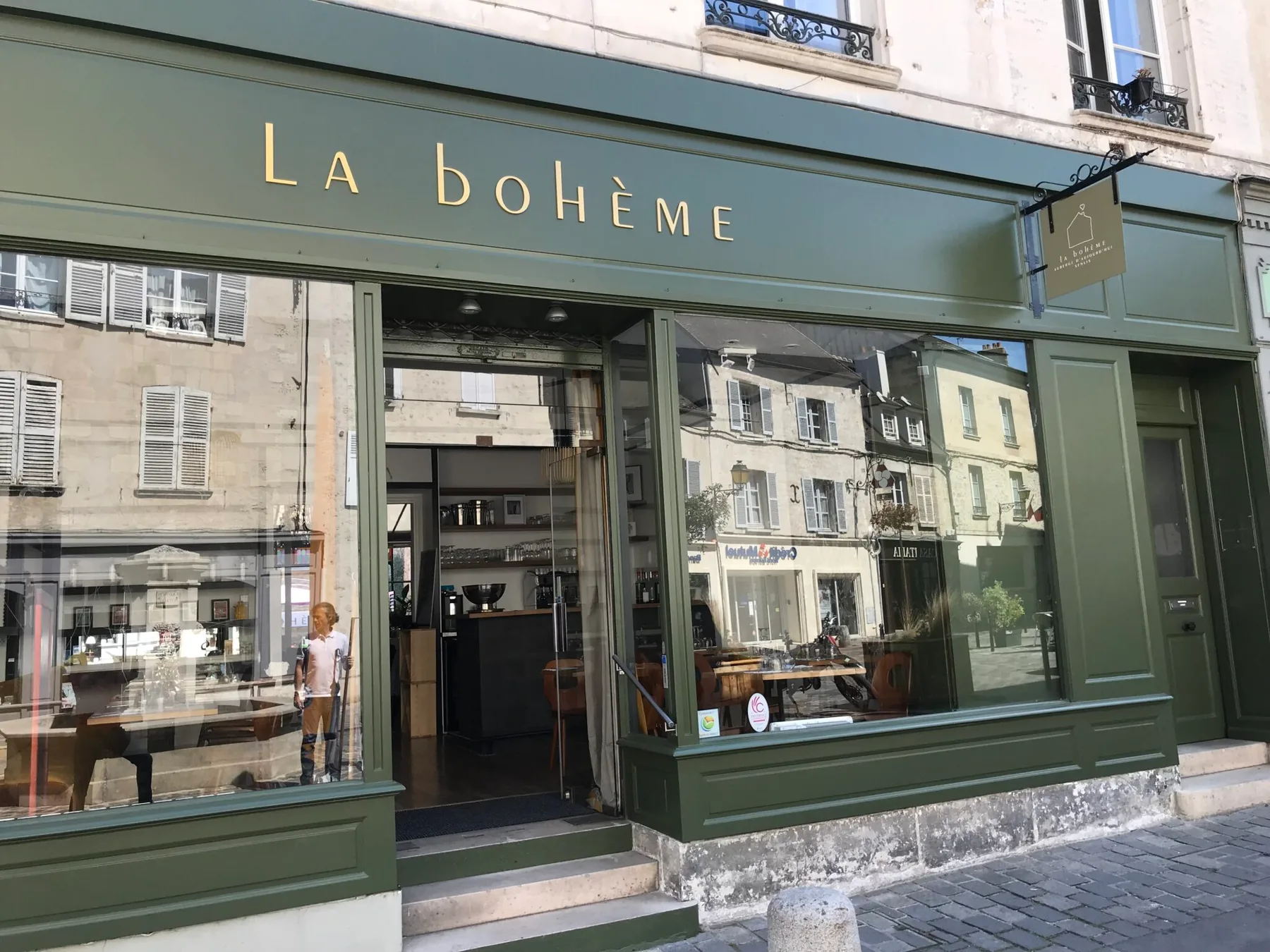 Espacio representativo del hotel: Un local con marcos verdes, grandes ventanales y el letrero La Bohème.