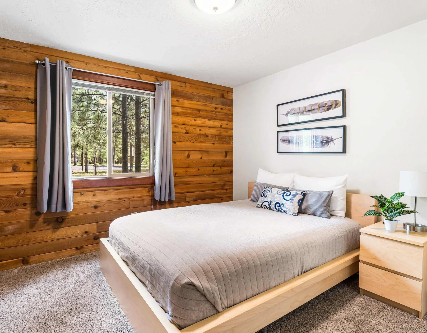 A bedroom with a bed beside a window framed by wood-paneled walls.