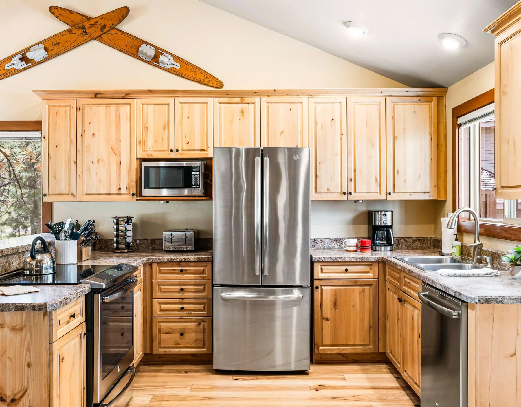 A bright kitchen with wooden cabinets, stainless steel appliances, and a central refrigerator.