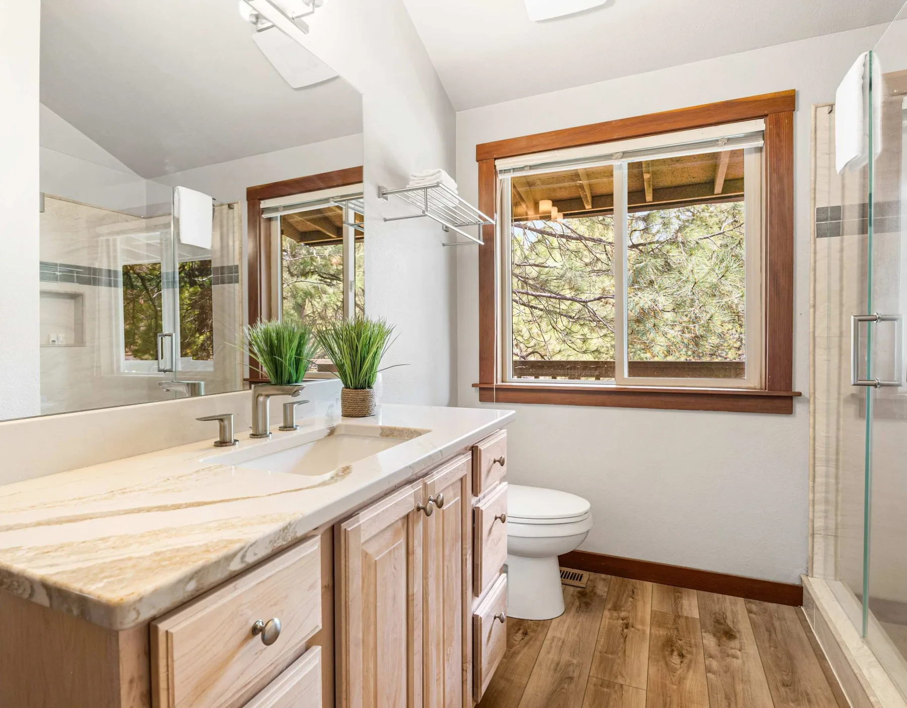 A bright bathroom with a long vanity, a toilet, and a window.
