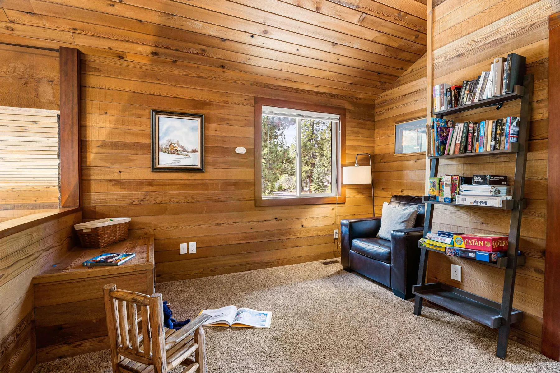 A wood-paneled room with a window, seating, and a bookshelf.