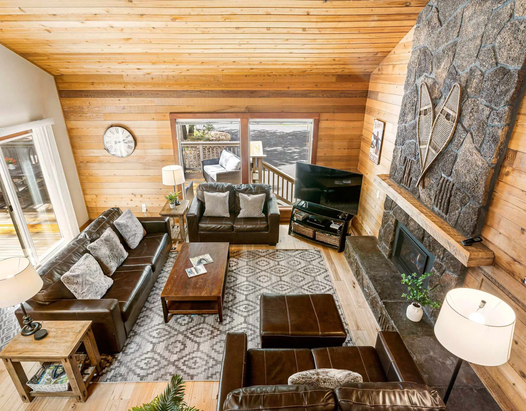A wood-paneled living room with leather seating and a stone fireplace.