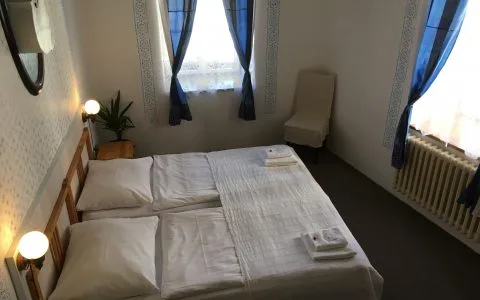 Representative hotel space: A bedroom with a neatly made bed and windows dressed with blue curtains.