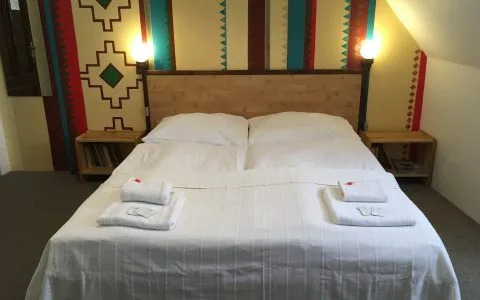 Representative hotel space: A bedroom with a neatly made bed beneath a colorful patterned wall.
