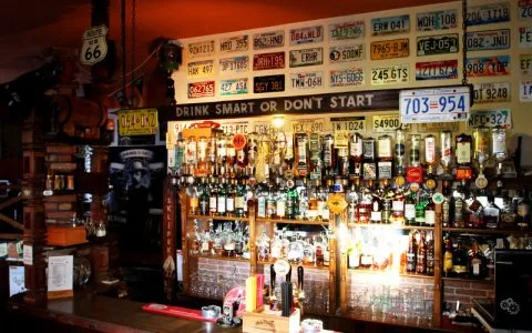 Representative hotel space: A bar counter displays bottles beneath a wall covered with license plates.