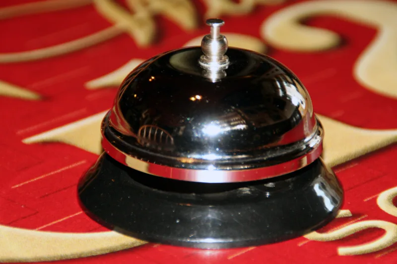 Representative hotel space: A polished service bell sits on a red patterned surface.