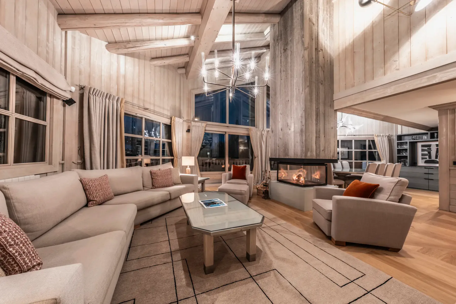 Una sala de estar amplia con asientos alrededor de una mesa de centro de vidrio y una chimenea.