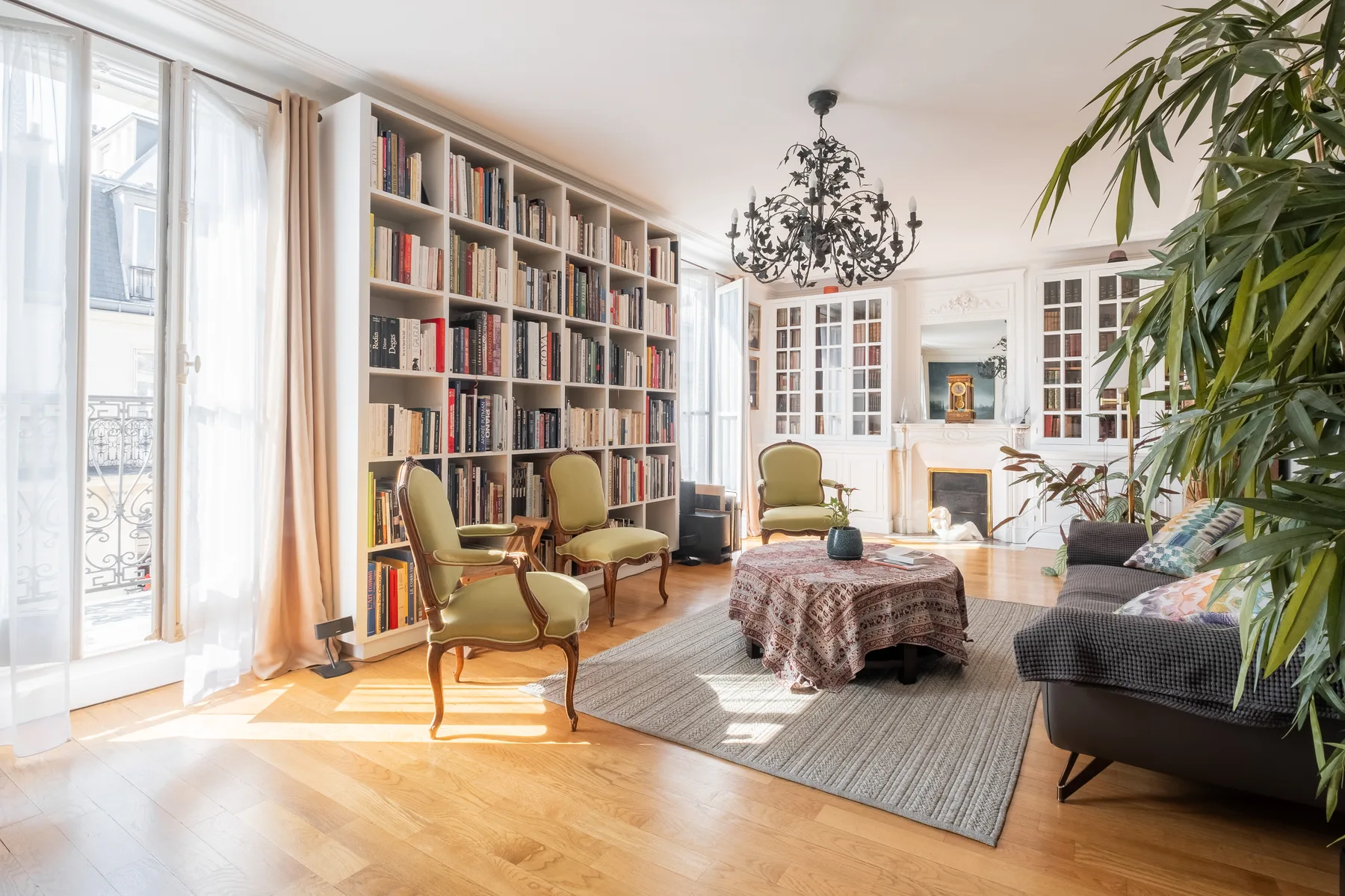A bright living room with a tall bookcase, seating, and a fireplace.
