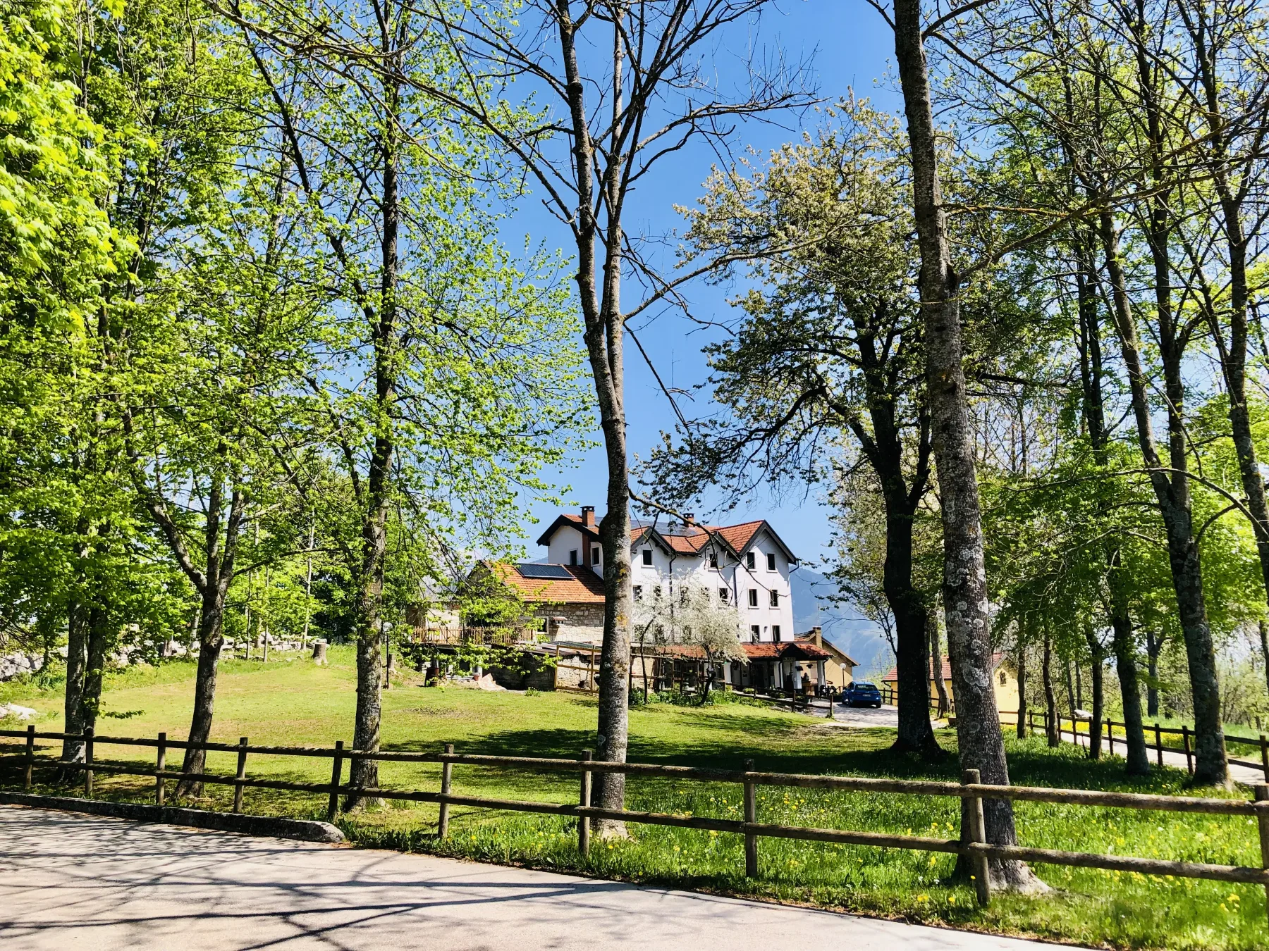 Representative hotel space: A large building stands among trees beside a grassy lawn.