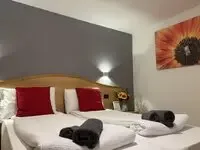 Representative hotel space: A hotel bedroom with a bed dressed in white linens and red accent pillows.