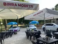 Representative hotel space: Outdoor dining area with tables and seating beneath umbrellas.