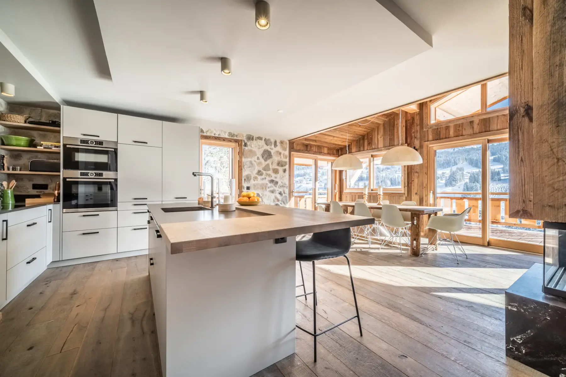 Una luminosa cocina abierta al comedor, con una isla grande y ventanas enmarcadas en madera.