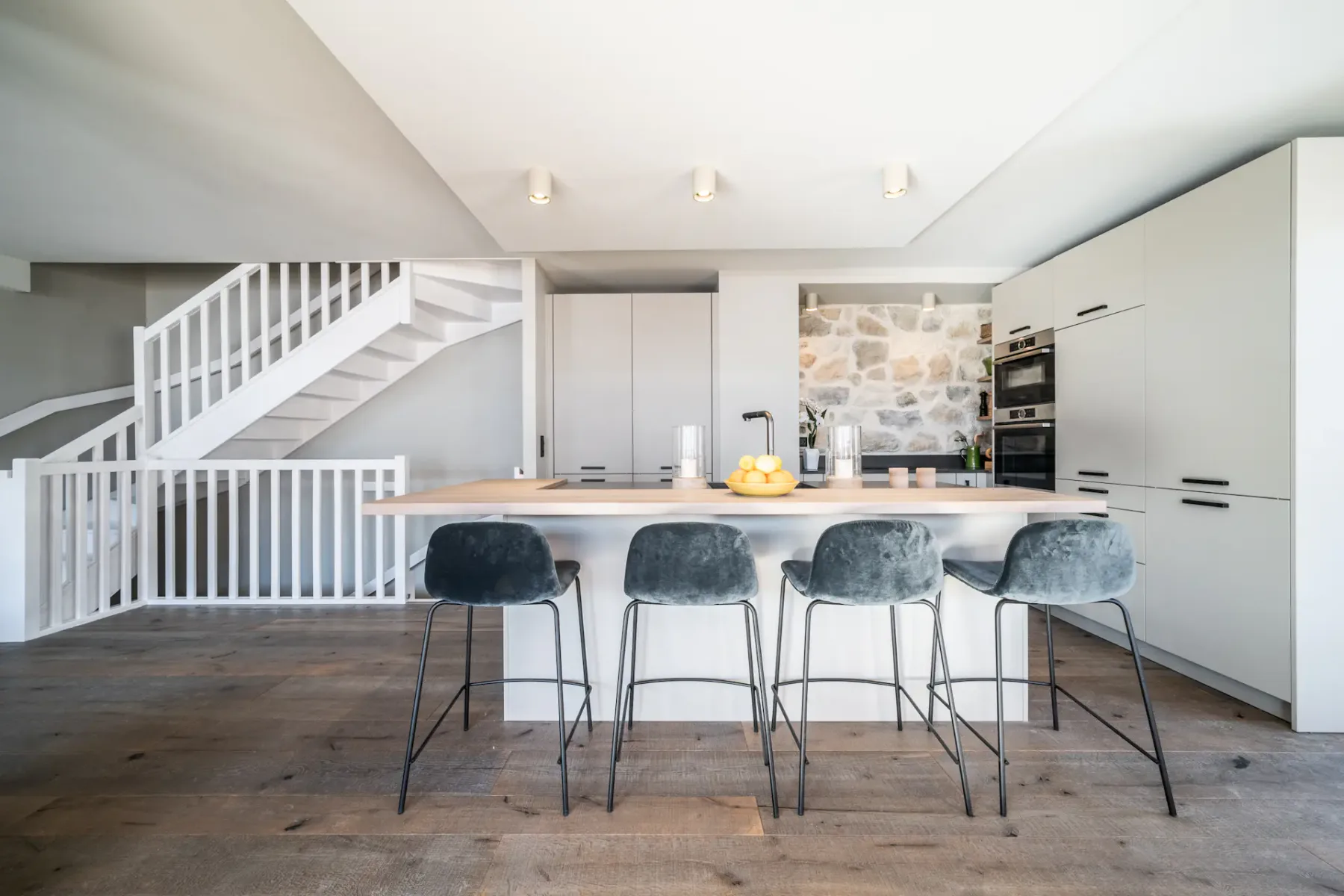 Una cocina luminosa cuenta con una isla central con asientos y armarios blancos.