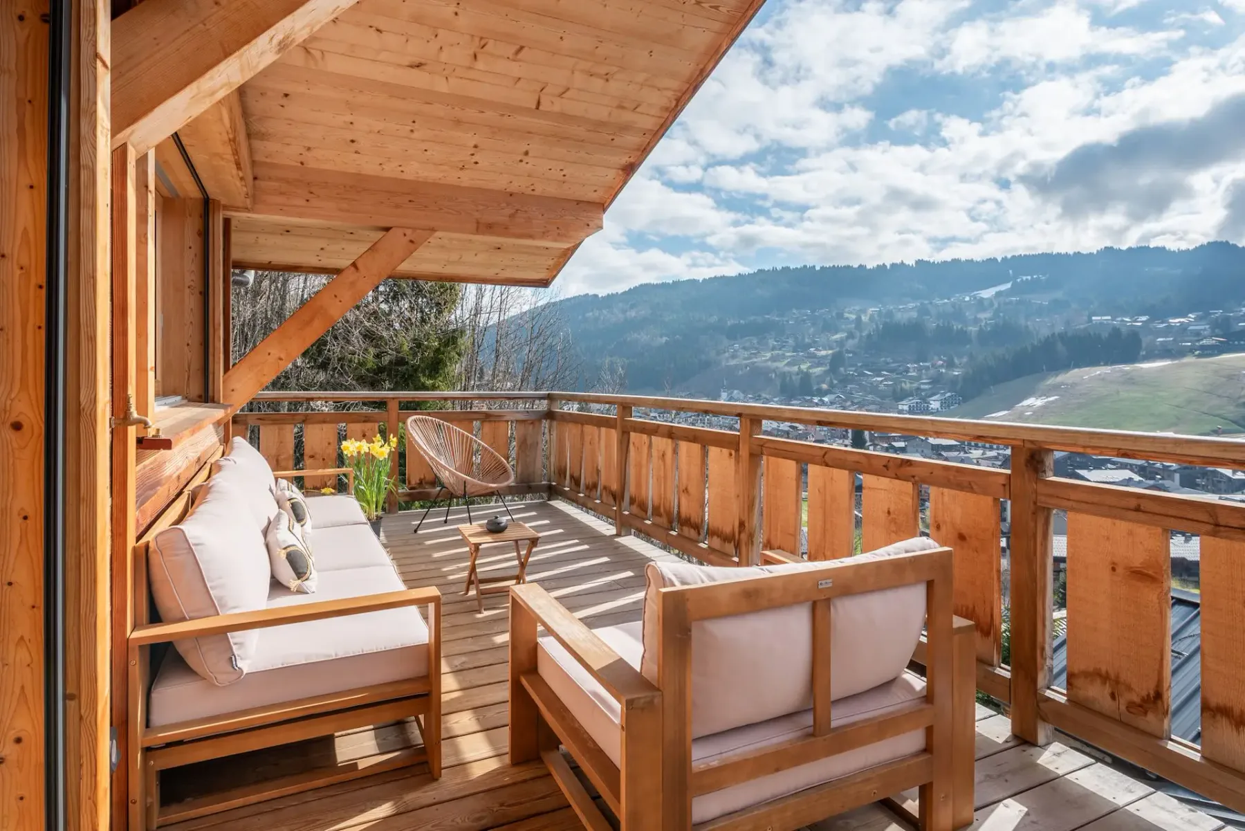 Un balcón de madera con asientos acolchados ofrece vistas a un paisaje montañoso.