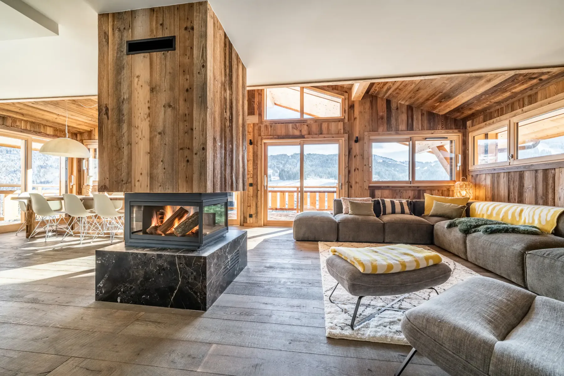 Una sala de estar revestida de madera con chimenea y asientos alrededor de una mesa baja.